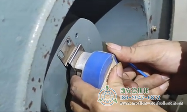 图为工作人员正在对发生飞车现象的电梯编码器进行拆御的照片