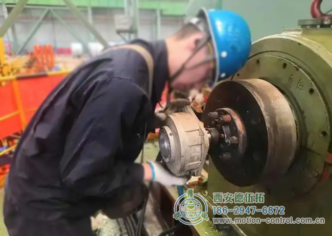 图为工人为彩涂酸轧轧机回装编码器的照片